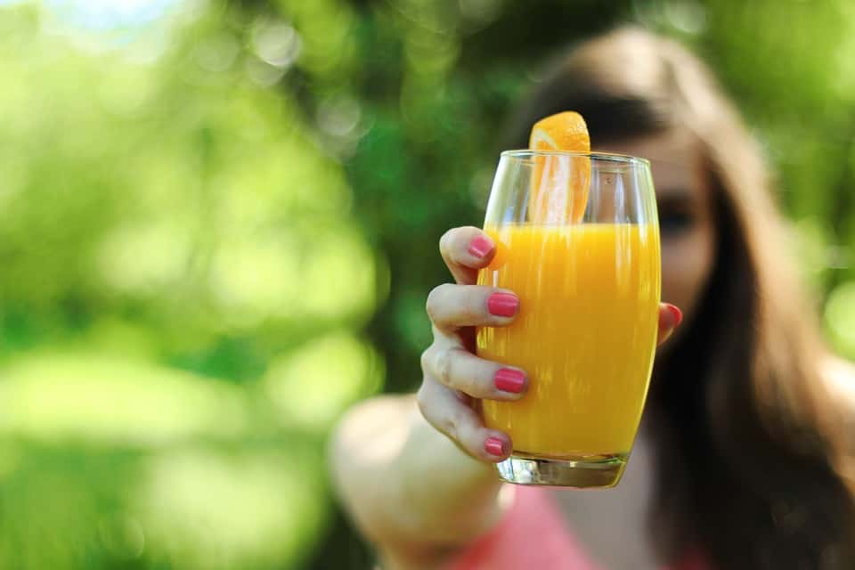 Lady holding a glass full of fresh citrus juice